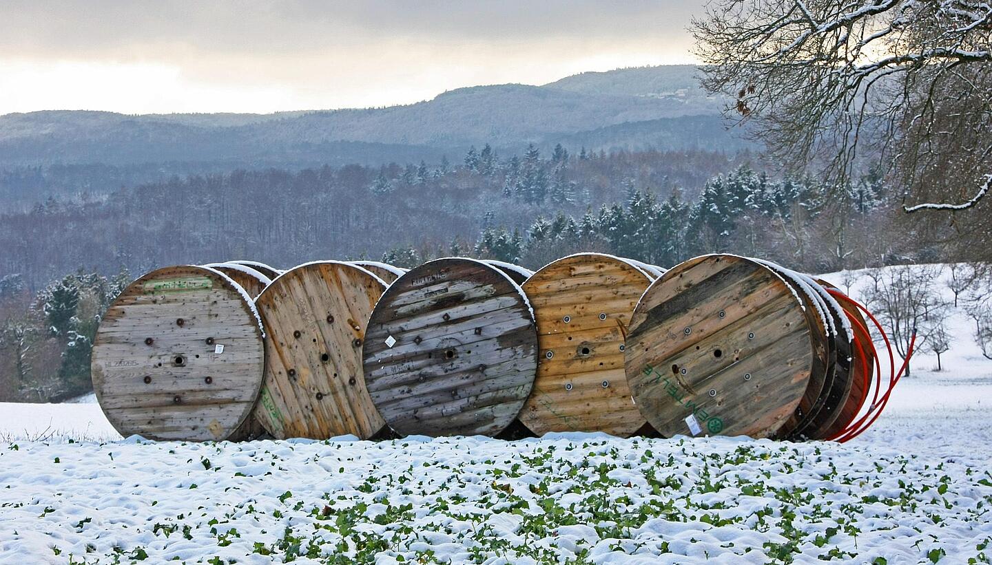 Fünf Kabelrollen in einer schneebedeckten hügeligen Landschaft.